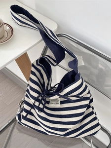 Blue and white striped canvas tote bag with drawstring detail on a modern chair