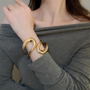 Close-up of a wide irregular geometric gold cuff bracelet on a female model wrist