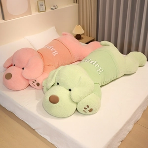 Large lying dog plush toy in pink and green sweaters on a cozy bed setting