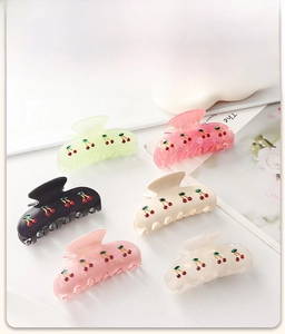 Detail of large colorful cherry hair claws in light green, pink and white finishes