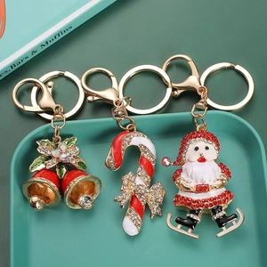 Close-up of festive crystal-studded Christmas bell, candy cane, and Santa keychains