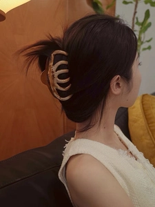 Detail view of a 13cm large amber claw clip styled on long hair in a cozy home setting