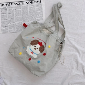 Detail of canvas tote bag featuring embroidered puppy motif and colorful pompoms