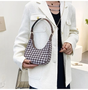 Houndstooth crescent bag shown on model with brown leather trim and metal zipper