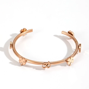 Detail of rose gold clover and Om symbol on a minimalist open cuff bracelet for women