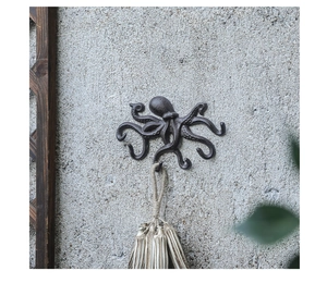 Detail eines Oktopus Wandhakens aus Gusseisen mit braunem Vintage-Finish auf grauer Wand
