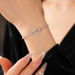Close-up of silver heart bracelet featuring a religious figure relief and sparkling zircons