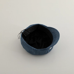 Detail of blue denim newsboy cap showing black inner lining and adjustable drawstring