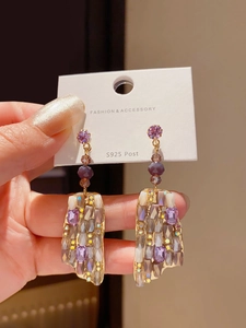 Close-up of S925 silver needle square purple crystal earrings held by hand on card