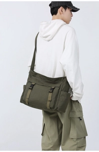 Détail d'un sac messager en toile vert armée avec bandoulière réglable et boucles en métal