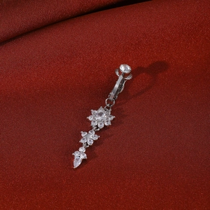 Macro detail of silver heart cross navel ring with sparkling zircons on red silk background