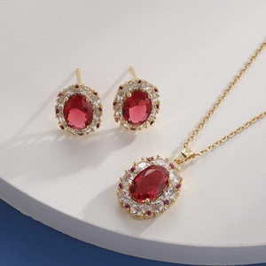 Macro detail of a gold ruby necklace and earring set on a white circular display stand