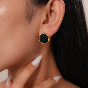 Close-up of vintage geometric gold-trimmed black flocked earring worn by a model