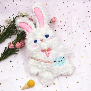 Détail de la trousse lapin en peluche blanche avec oreilles roses et nœud bleu