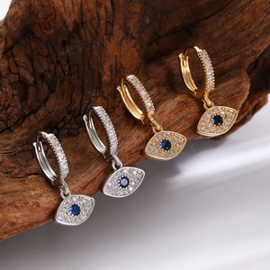 Gold and silver evil eye hoop earrings with blue stones on natural wood background