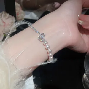 Macro detail of French zircon flower and pearl bracelet on wrist with elegant black backdrop
