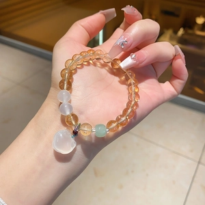 Detail view of crystal bead bracelet featuring a white jade apple charm and amber beads