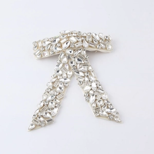 Detailed close-up of handmade bow hair clip with luxury rhinestones and pearl accents