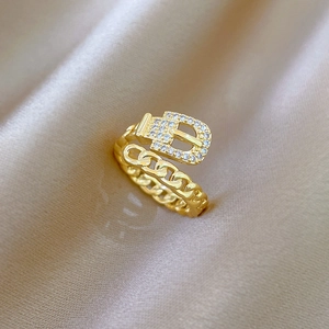Detailed close-up of golden belt-chain ring with sparkling zircon inlays on silk