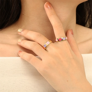 Close-up of gold plated rings with colorful enamel hearts worn by a fashion model
