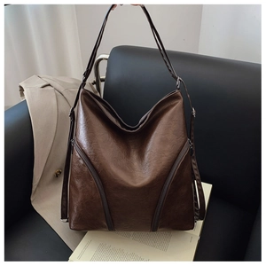 Detail of dark brown faux leather tote bag with functional double diagonal zippers