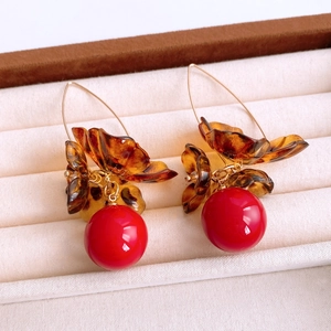 Vue macro de boucles d'oreilles vintage en résine avec pétales ambrés et perles rouges