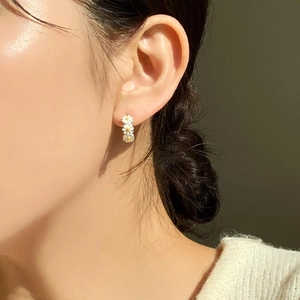 Close-up of a model wearing minimalist small daisy stud earrings in 925 sterling silver