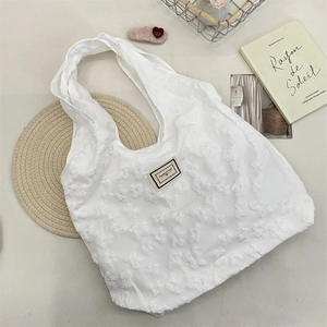 Detail of white jacquard tote bag with 3D floral texture and PLEASANT TIME logo label