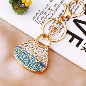 Close-up of gold handbag keychain with blue and white crystals and silk background