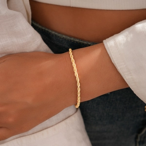 Détail d'un bracelet chaîne corde doré avec texture vintage porté par une femme