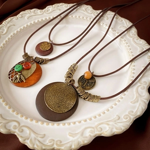 Detail view of ethnic long necklaces with wood beads and vintage copper charms on ceramic