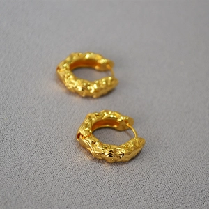 Macro detail of gold lava texture hoop earrings showing unique hammered metal surface