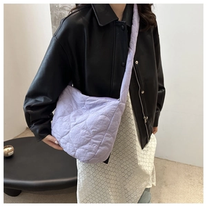 Detail of light purple quilted tote bag with diamond stitching worn by model in leather jacket