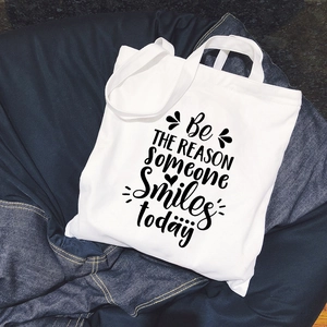 Minimalist white canvas tote bag with black inspirational lettering on denim background