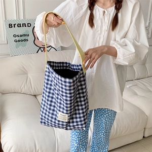 Detail of blue and white checkered canvas tote bag with bright yellow strap and logo
