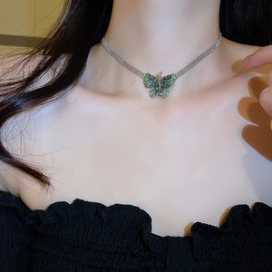 Detailed close-up of a butterfly pendant necklace with blue and green crystals on model
