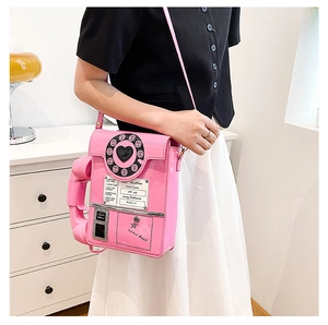 Pink retro telephone shaped crossbody bag with Hotline print in a stylish interior room