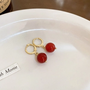 Makroaufnahme minimalistischer roter Perlenohrringe mit eleganten goldplattierten Verschlüssen