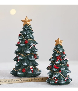 Close-up of resin mini Christmas trees with gold stars, candy canes and warm light decor