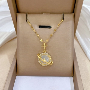 Detailed close-up of golden planet necklace with cat's eye stone and pavé crystal accents