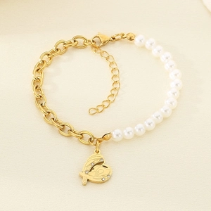 Detail view of heart pendant with angel wings on pearl and gold link chain bracelet