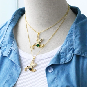 Detail of colorful hummingbird pendant necklace with micro-paved crystals on a model