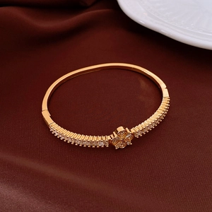 Dettaglio di un bracciale dorato con fiori in zircone su sfondo di seta rosso lussuoso