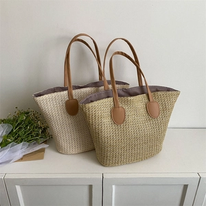 Large straw tote beach bag with brown leather handles in beige and khaki colors