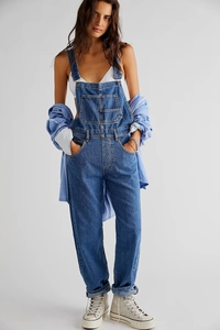 Detail shot of dark blue denim overalls featuring adjustable buckles and side pockets