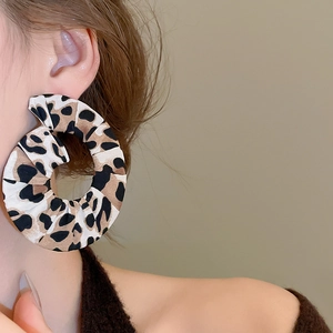 Close-up of leopard print fabric circle drop earrings worn by a model in profile view
