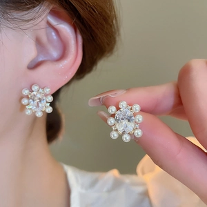 Detail of 14k gold plated flower stud earrings with oval zircon and pearl accents