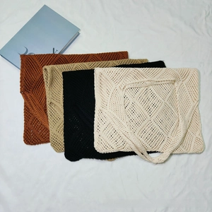 Flat lay of hollow knit tote bags in caramel, khaki, black, and beige on white fabric