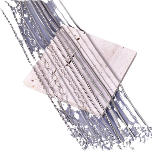 Polished silver stainless steel cuban and snake chain necklaces on a textured stone base