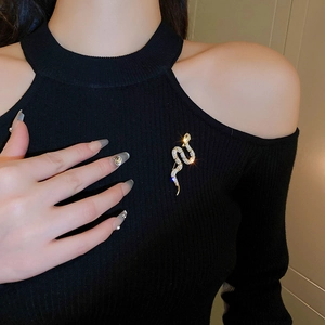 Elegant gold snake brooch with sparkling zircons worn on a black sweater for women